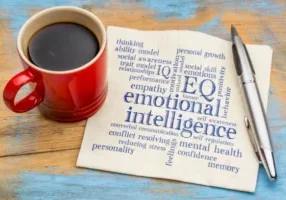 Coffee, pen, emotional intelligence words on napkin.