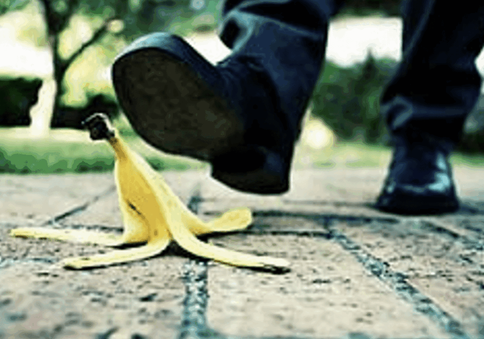Foot approaching banana peel on pavement.