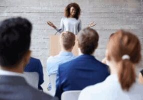 Smiling speaker addresses attentive audience at podium