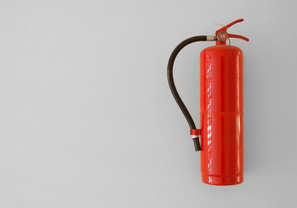 Red fire extinguisher on white wall.