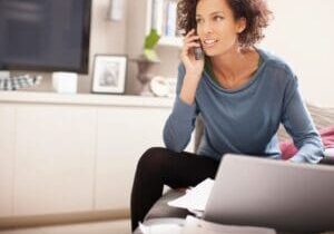 Woman talking on phone, working on laptop.