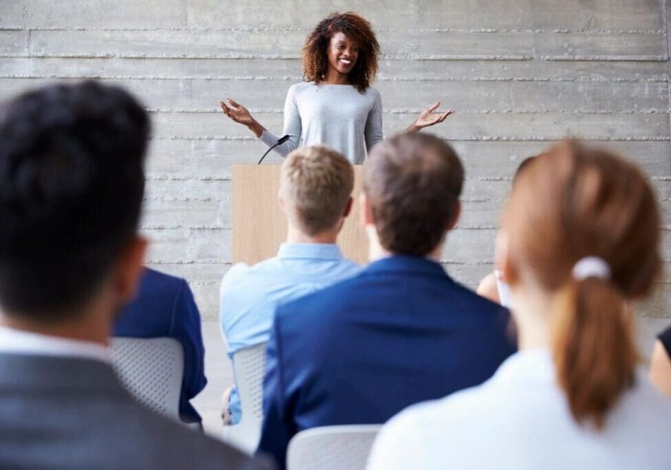 Woman presenting at podium to attentive audience